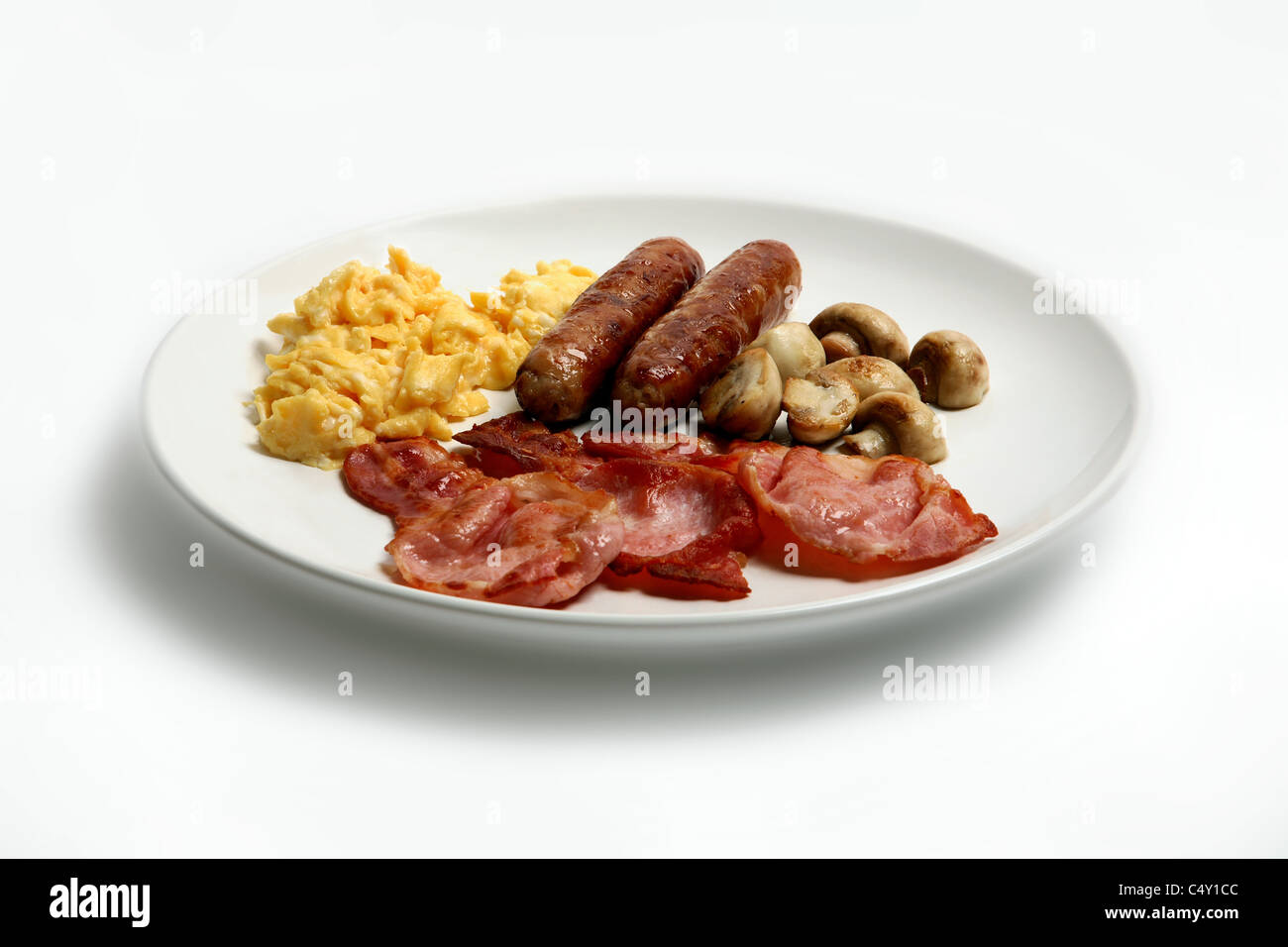 Saucisses, bacon, champignons et œufs brouillés sur une plaque blanche Banque D'Images