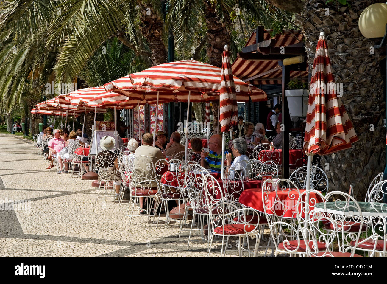 Gens touristes visiteurs assis à des tables à l'extérieur dans un café en plein air sur la promenade front de mer Funchal Madeira Portugal eu Europe Banque D'Images