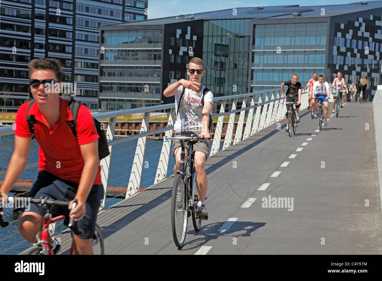 Heureux garçons ou jeunes sur des vélos qui passent le long de 190 m et 5,5 m de large vélo et pont piétonnier en acier au-dessus du port de Copenhague, Danemark. Banque D'Images