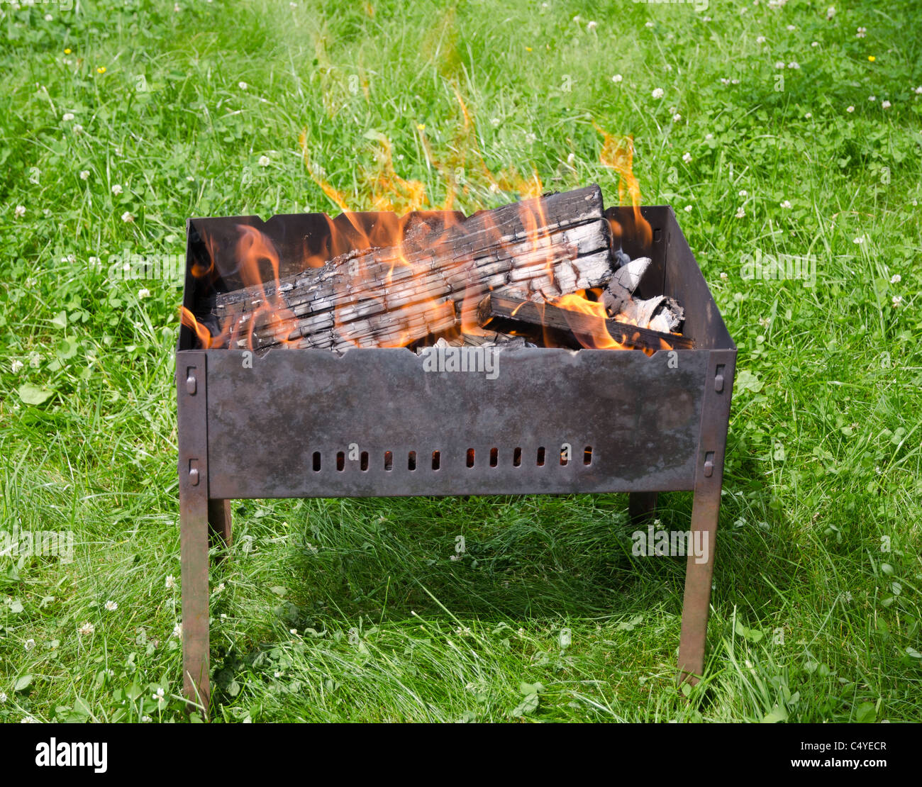 Vue rapprochée de l'incendie dans les langues sur un barbecue jardin herbe verte Banque D'Images