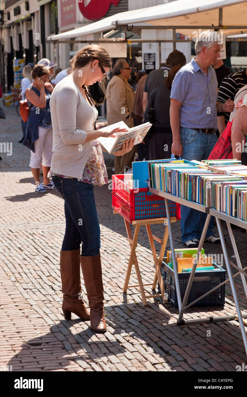 Jeune femme à la recherche de livres dans la Grand-place ou market place Haarlem, Hollande du Nord, Pays-Bas. JMH5058 Banque D'Images