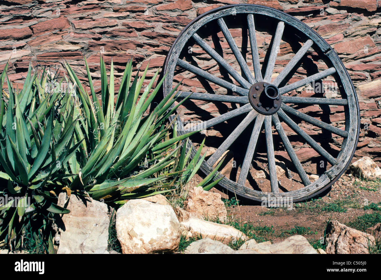 Ancienne roue de chariot en bois contre le mur en pierre au village du Grand Canyon, le Parc National du Grand Canyon, Arizona Banque D'Images