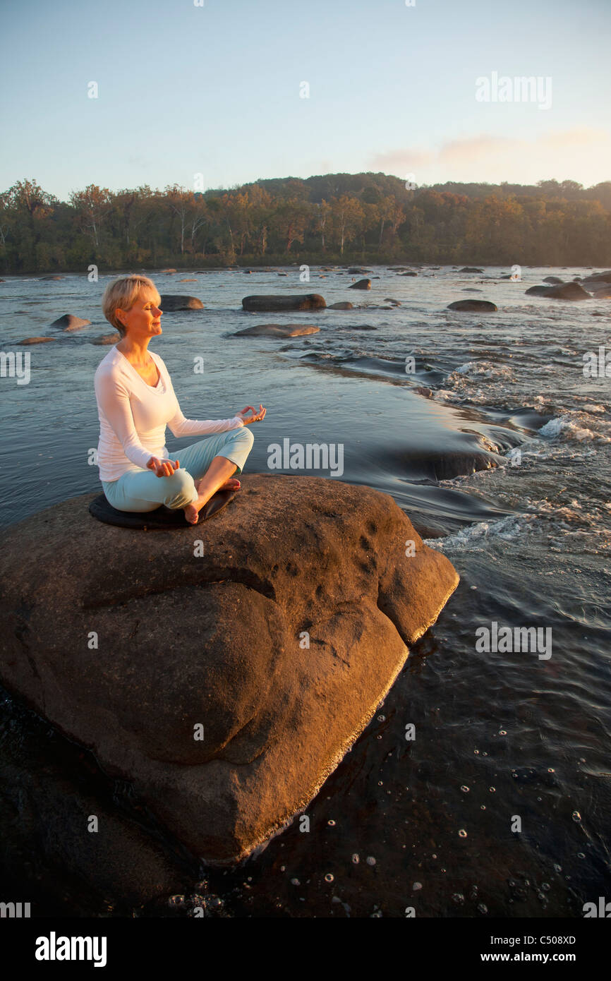 Caucasian woman practicing yoga on rock près de ocean Banque D'Images