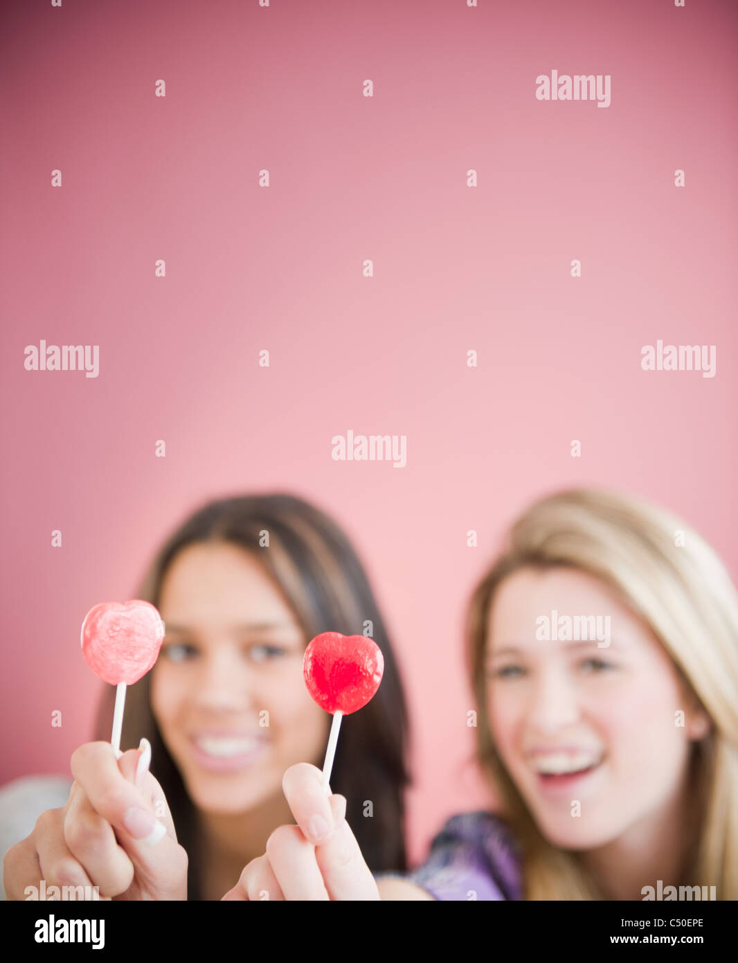 Teenage Girls holding heart-shape lollipops Banque D'Images