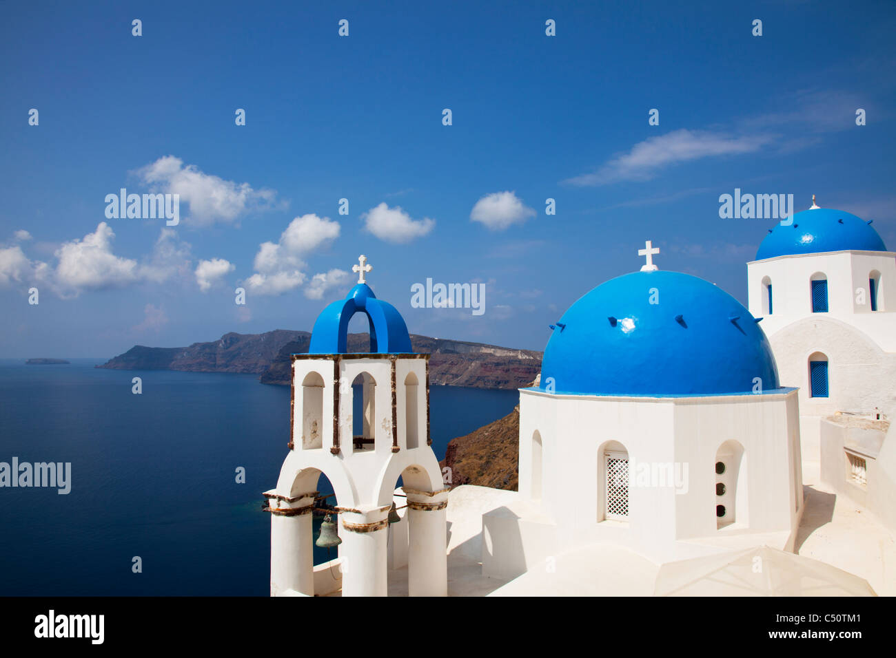 Typique de Santorin île grecque emblématique église au dôme bleu et clocher contre la mer et la Caldeira à Oia Banque D'Images