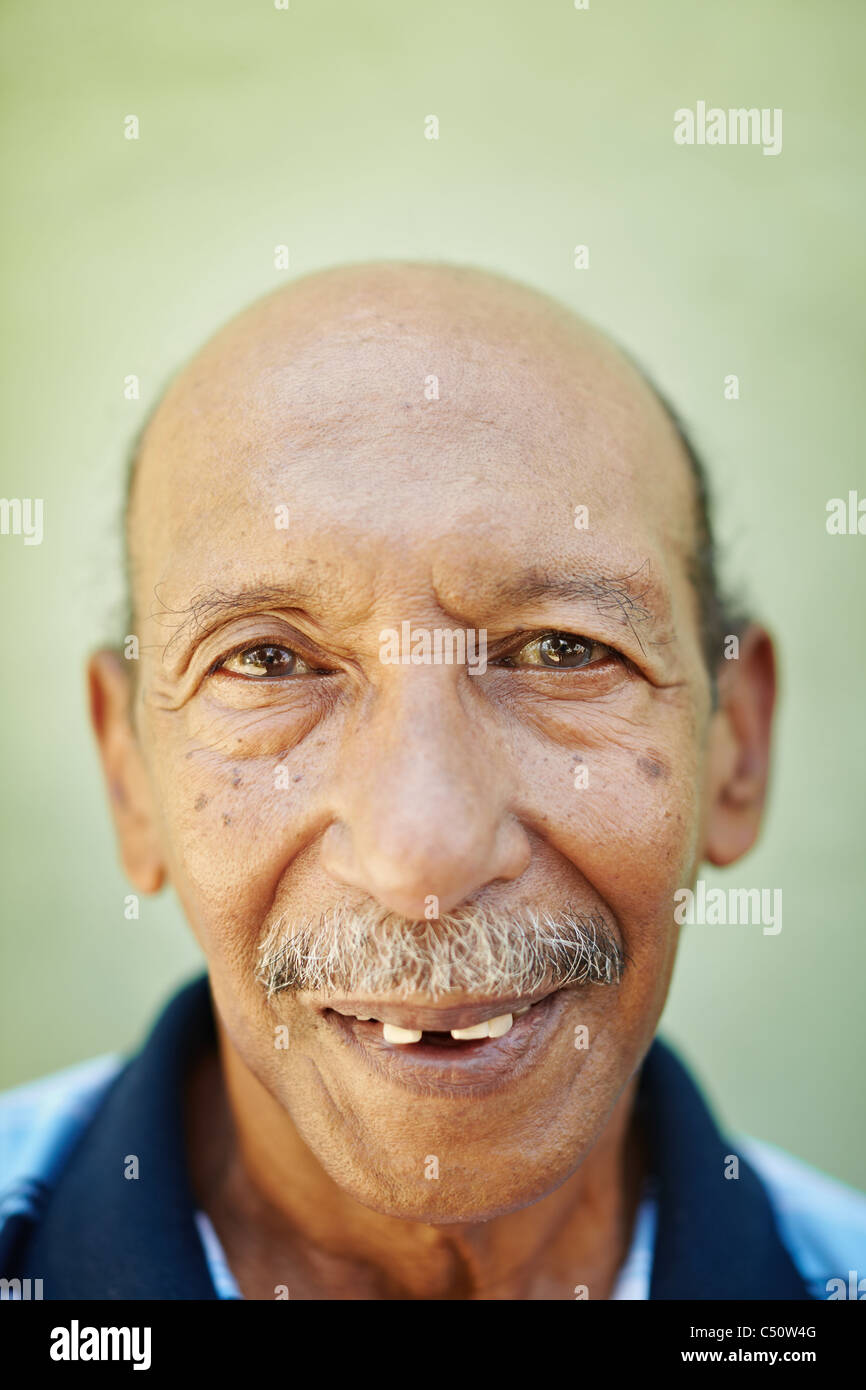 Portrait of senior hispanic man avec des problèmes dentaires looking at camera contre mur vert. La forme verticale Banque D'Images