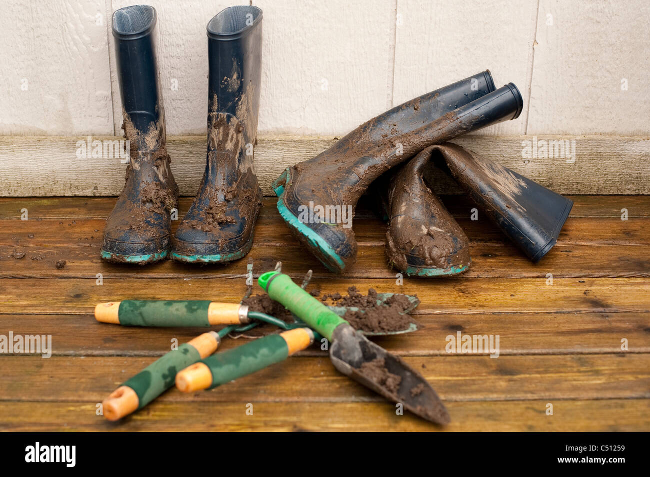 Des bottes et des outils de jardinage sur terrasse arrière après avoir travaillé dans le jardin. Banque D'Images