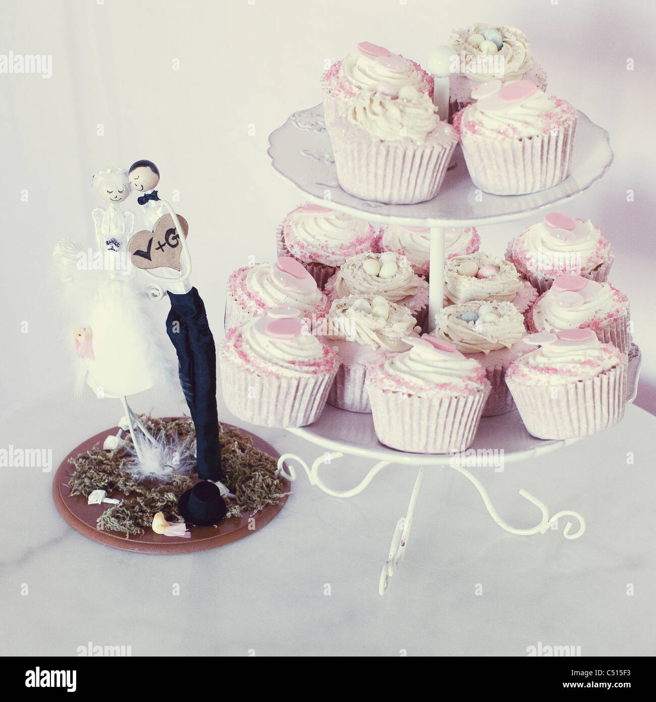 Petits gâteaux de mariage on cake stand à côté de Bride and Groom cake topper Banque D'Images