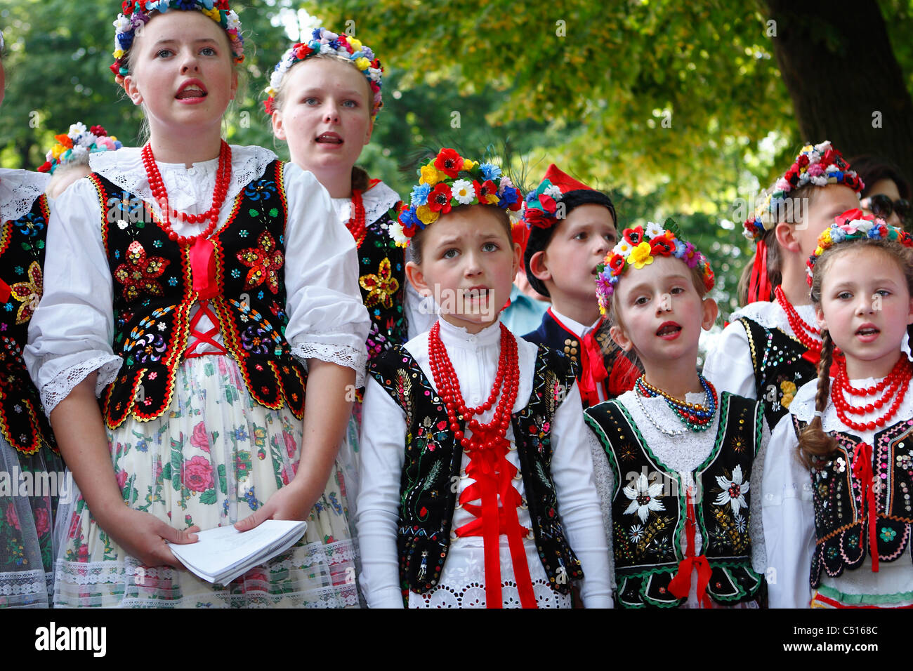 Un groupe d'enfants en costumes folkloriques traditionnels de style de Cracovie au cours d'une exécution musicale. Banque D'Images