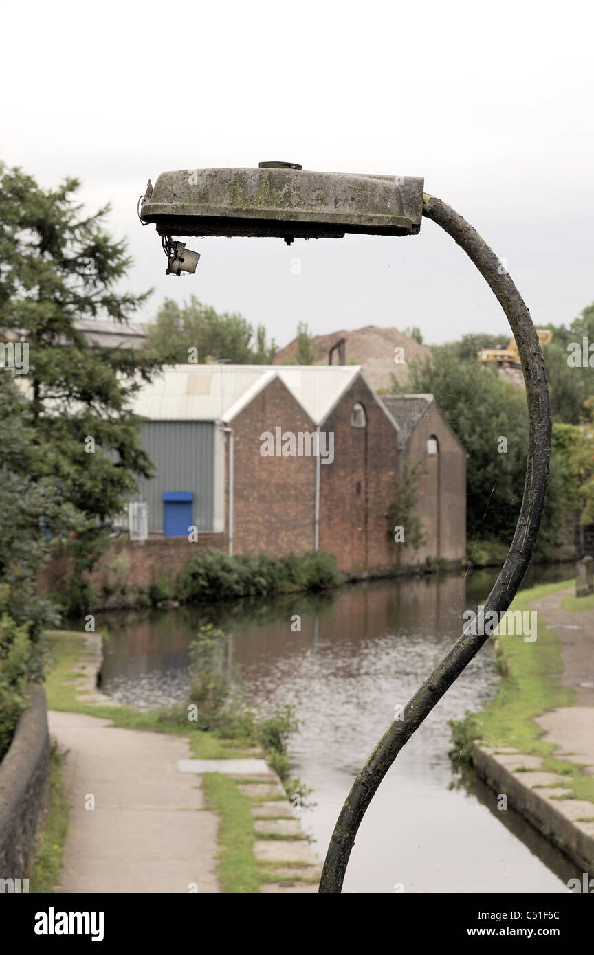Broken street light en premier plan de canal et l'usine industrielle avec les chemins de halage et d'autre bâtiments Banque D'Images
