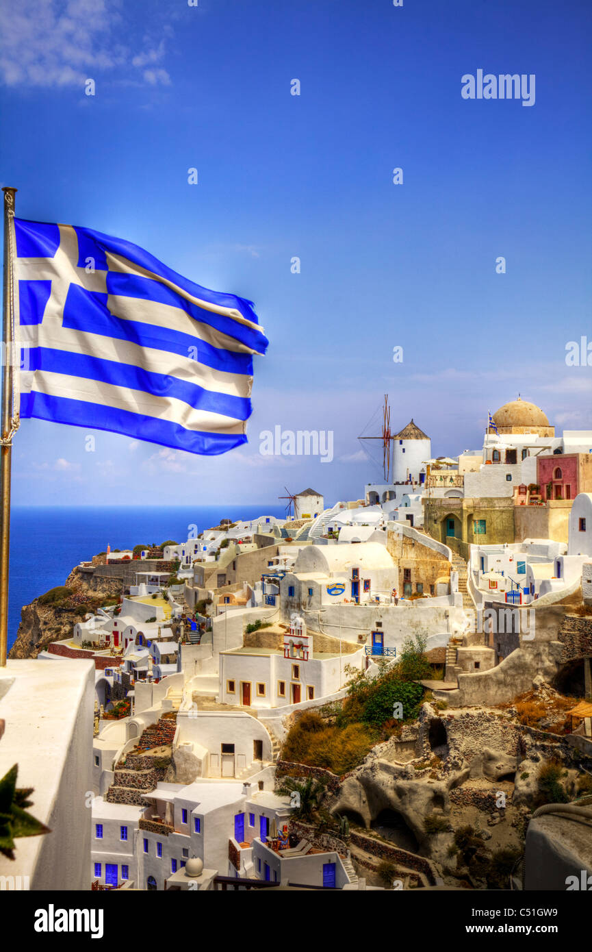 Drapeau grec battant ses couleurs à Oia, Santorin, l'île emblématique de la Grèce Banque D'Images