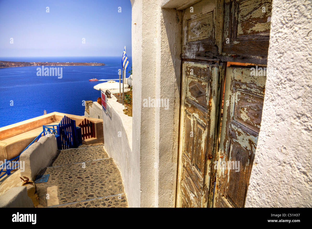 Drapeau grec battant ses couleurs à Oia, Santorin, l'île emblématique de la Grèce Banque D'Images