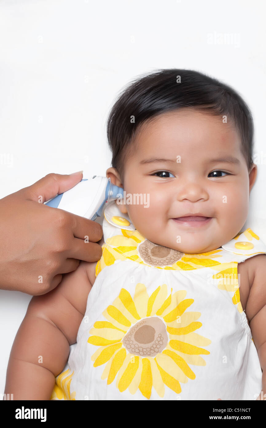 Happy Baby fille obtenant pris la température en utilisant un thermomètre auriculaire Banque D'Images