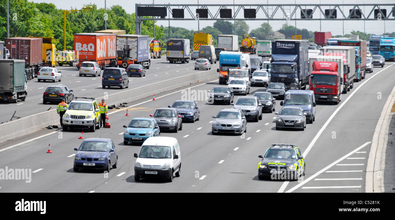 Autoroute M25 Essex voiture de police arrive sur scène d'accident de voiture en aval du pont Highways Agency d'éliminer les débris d'attente de trafic de camions camions voitures UK Banque D'Images
