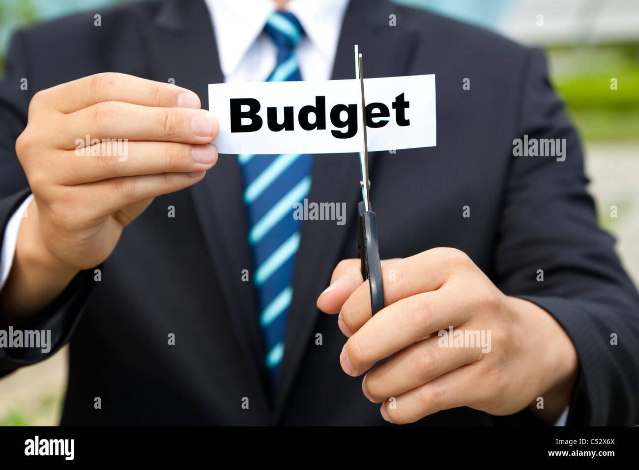 Businessman avec des ciseaux couper le budget de l'étiquette Banque D'Images