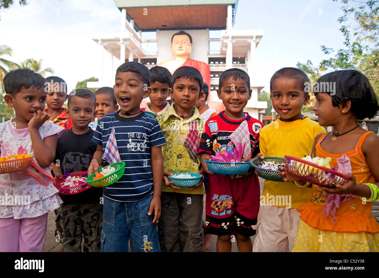 Les enfants avec des offres pour la statue du Bouddha géant dans l'Weherahena temple de Matara, au Sri Lanka, en Asie Banque D'Images