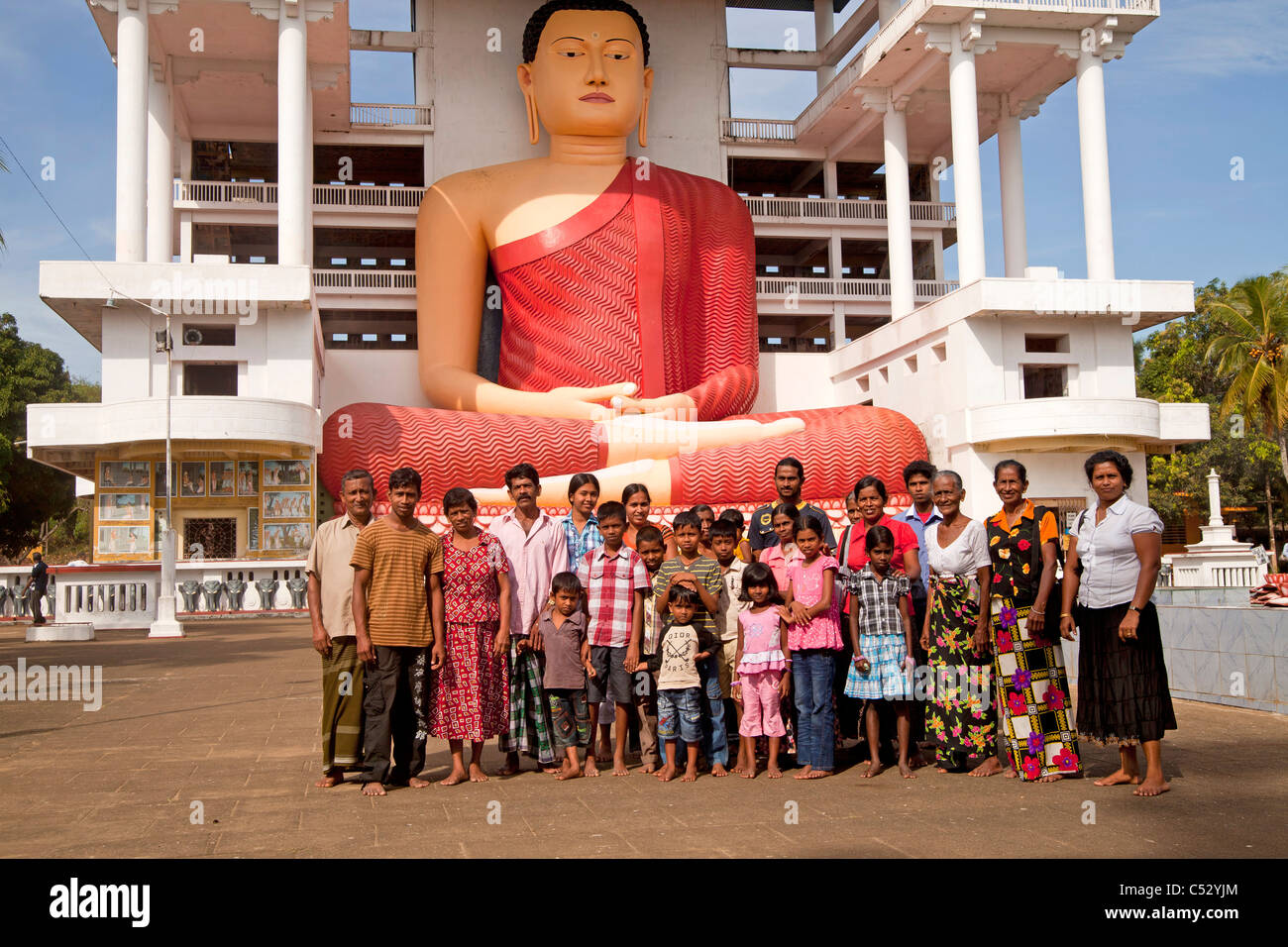 La famille élargie des Cinghalais en face de la gigantesque statue de Bouddha assis dans le temple de Weherahena Matara, au Sri Lanka, en Asie Banque D'Images