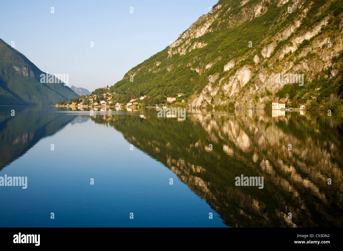 Village de Cima reflète dans les eaux calmes du lac de Lugano tiré de Porlezza Banque D'Images