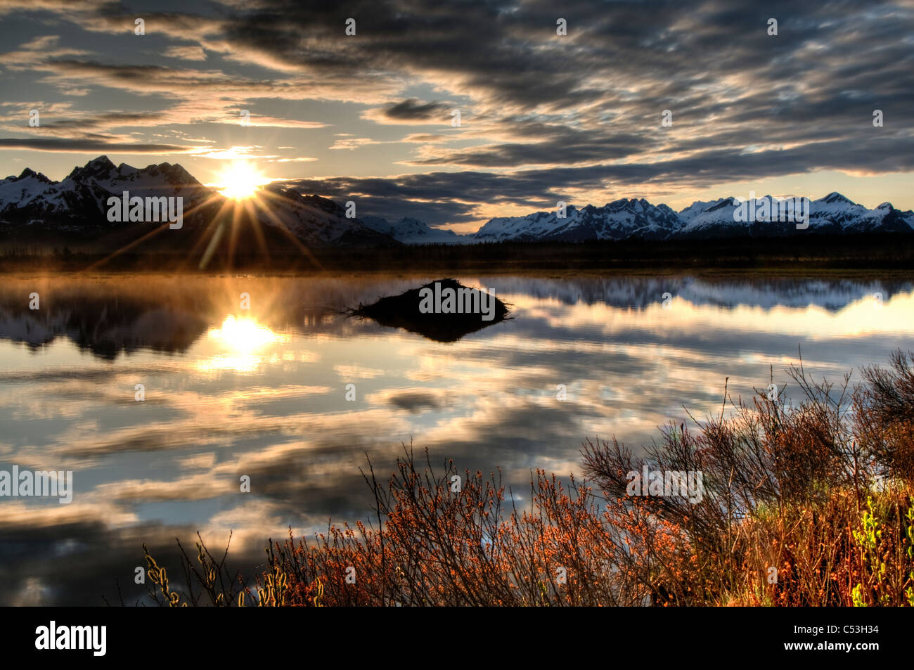 Soleil se lève sur les montagnes Chugach, avec un étang et Beaver Lodge au premier plan, l'Alaska, la Forêt Nationale de Chugach Banque D'Images