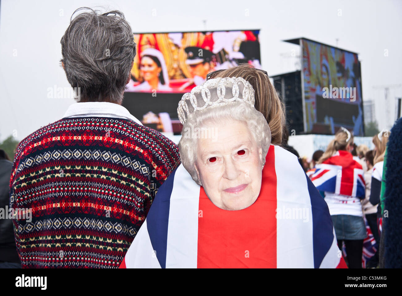 Les gens célébrant il Mariage Royal dans Hyde Park avec Union Jack flag et le masque de la Reine. Banque D'Images