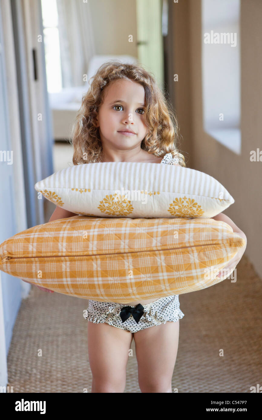 Portrait of a cute little girl holding oreillers à la maison Banque D'Images