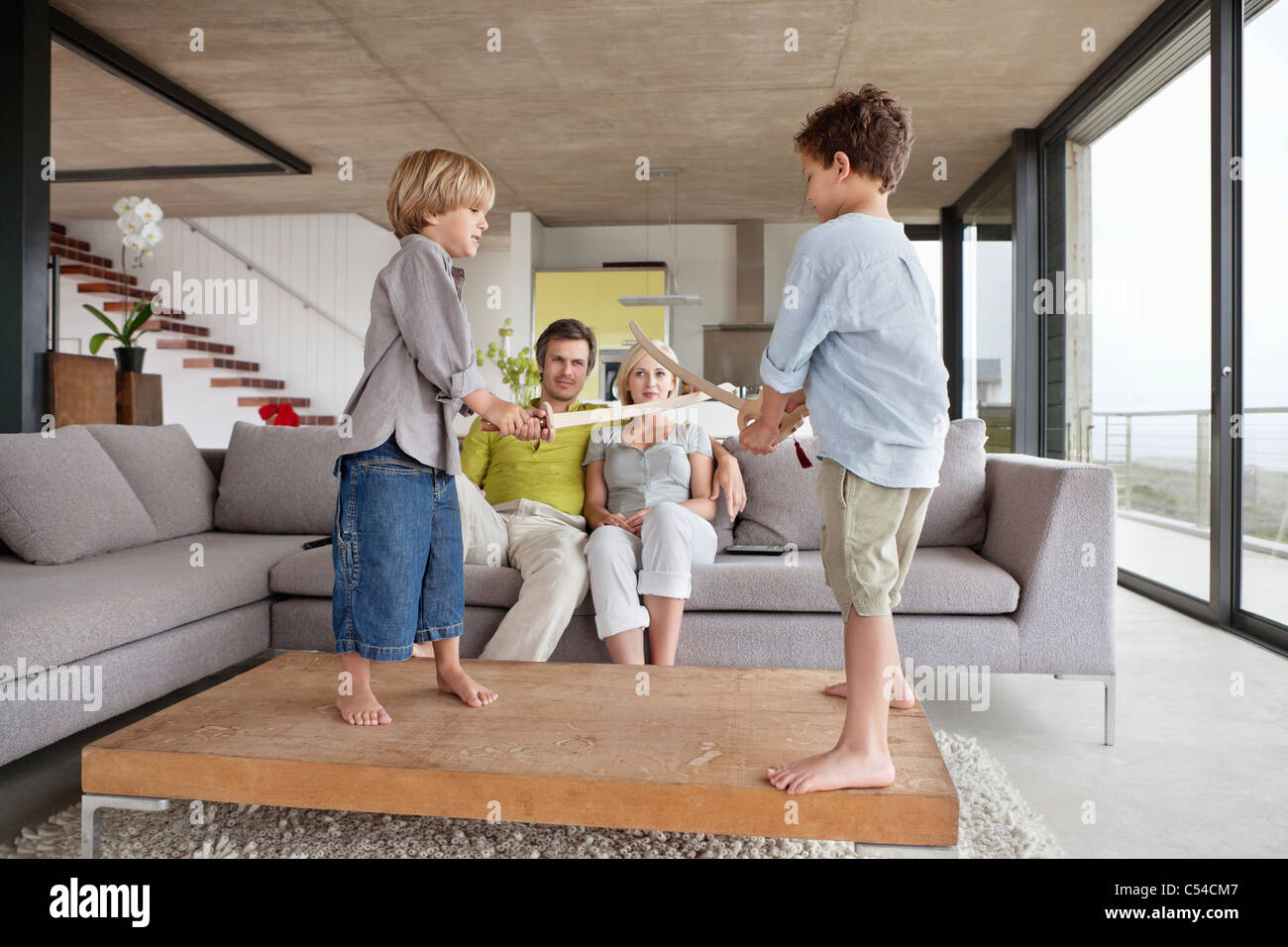 Garçons jouant avec leurs parents assis sur un canapé Banque D'Images