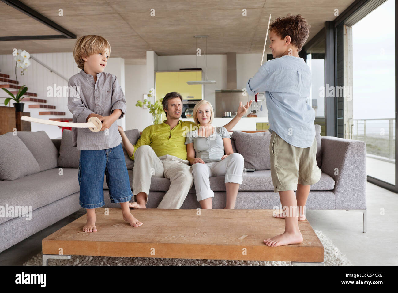 Garçons jouant avec leurs parents assis sur un canapé Banque D'Images