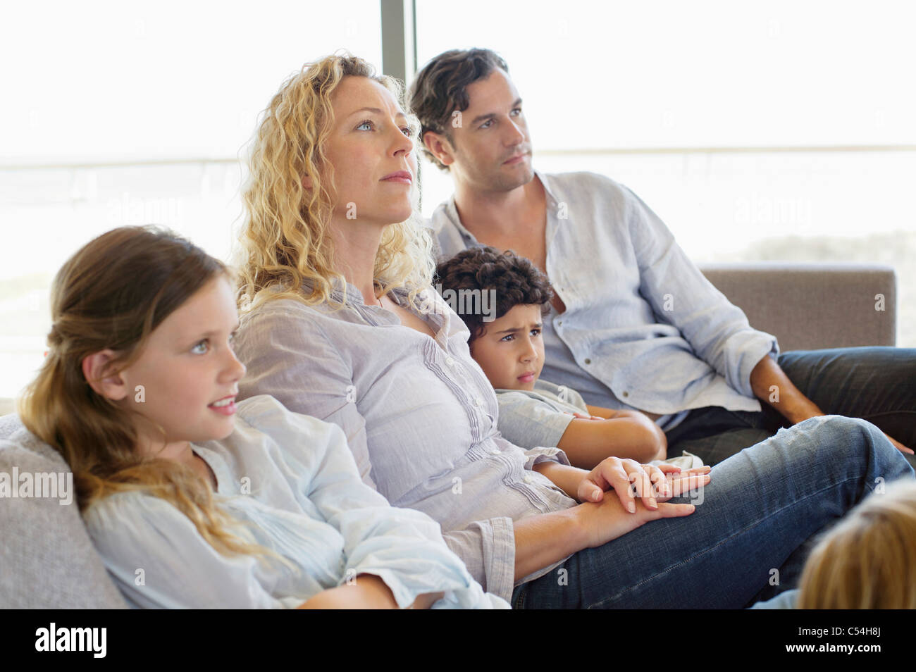 Famille avec trois enfants assis sur un canapé Banque D'Images