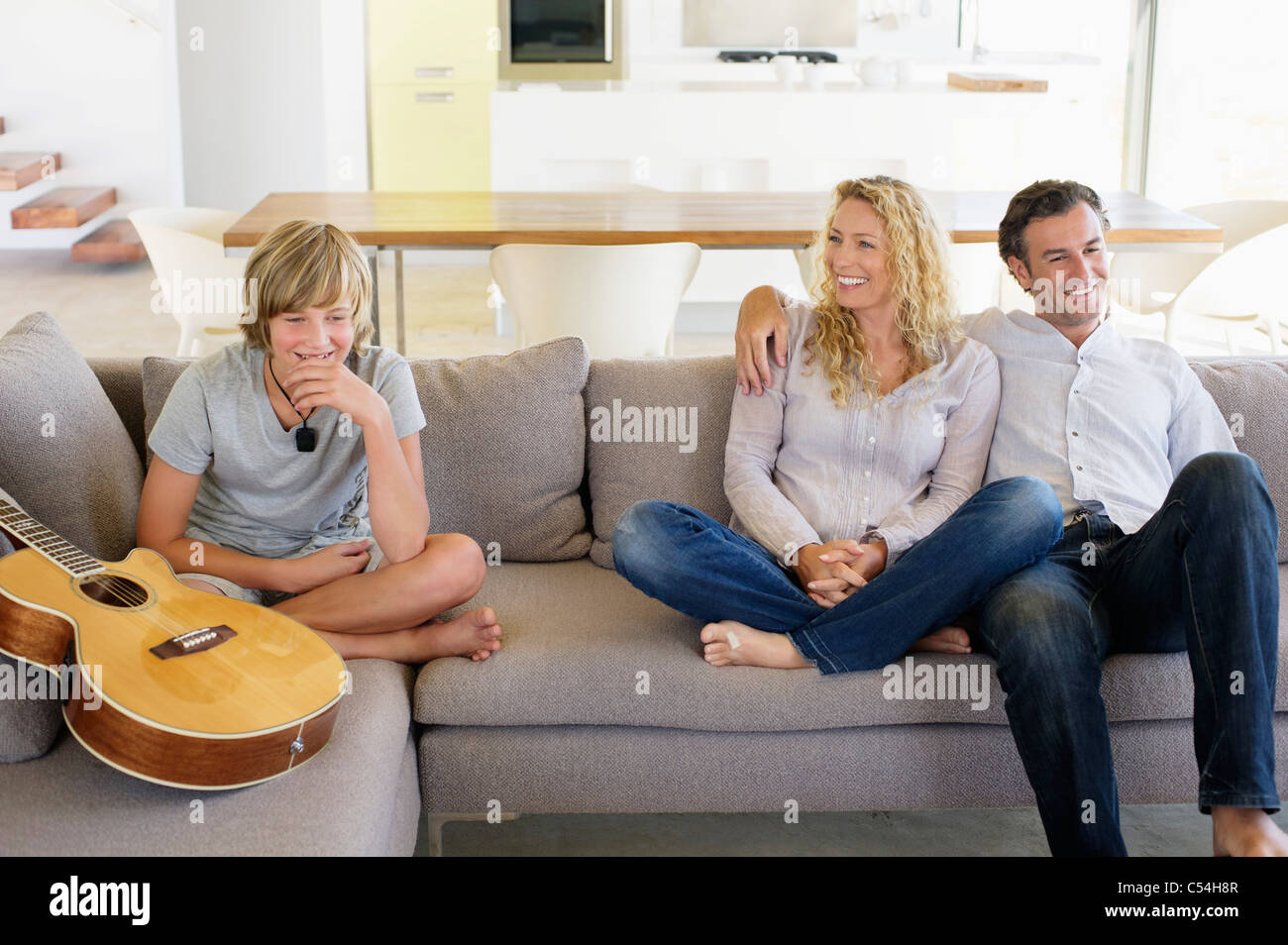 Family sitting on a couch and smiling Banque D'Images