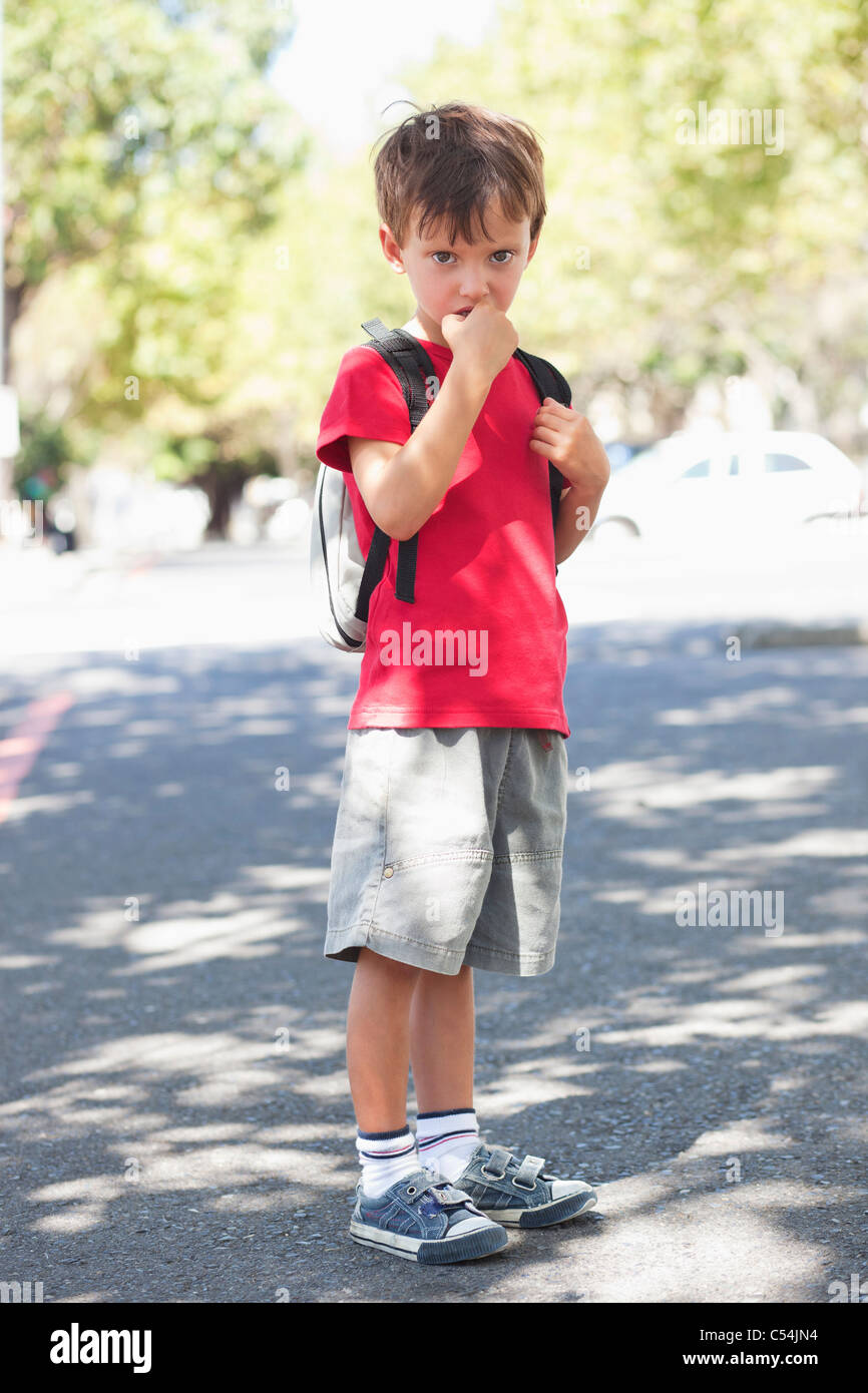 Portrait of a cute little boy standing with finger in mouth Banque D'Images