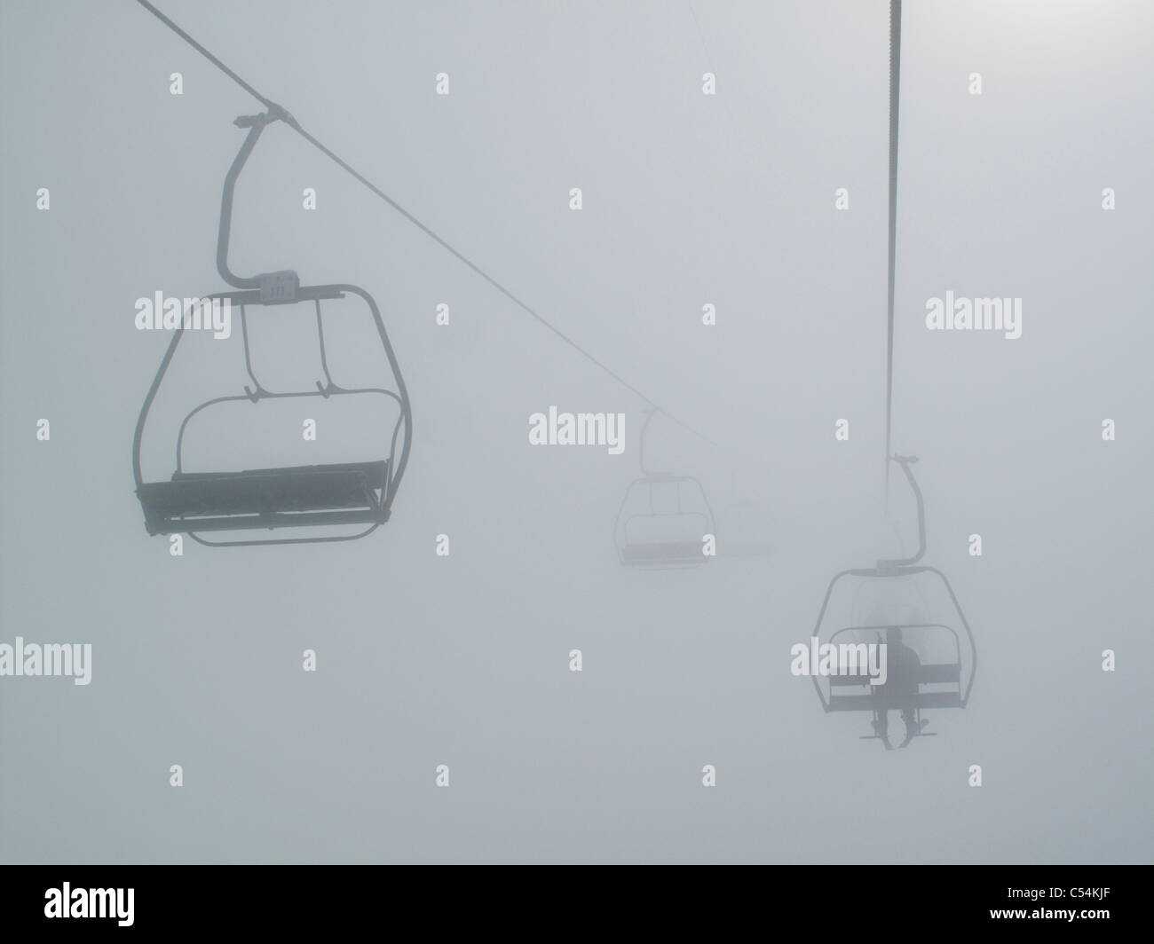 Un skieur est assis sur un télésiège dans la brume dans la station française de Morillon Grand Massif dans la région du Rhone Alpes Banque D'Images