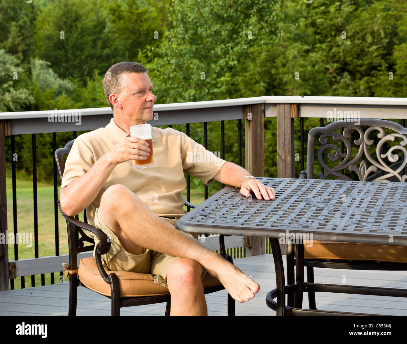 Man drinking beer assis sur un pont dans le jardin / cour arrière, USA Banque D'Images