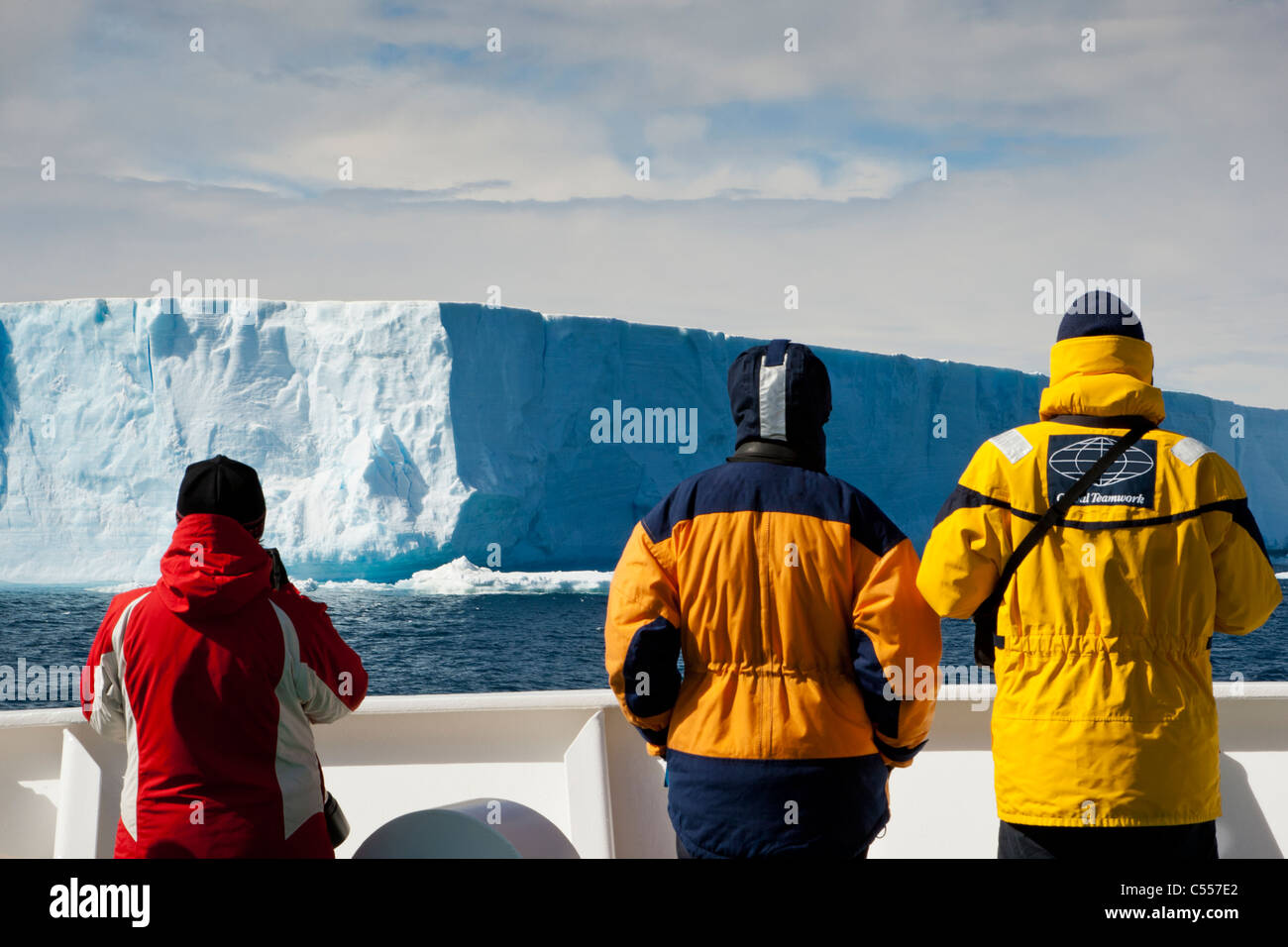3 Gros plan sur les passagers de croisière expédition en Antarctique à l'extérieur les officiers de pont regarder comme iceberg bleus géants dans l'Antarctique par des flotteurs portant des parkas Rouge & Jaune Banque D'Images