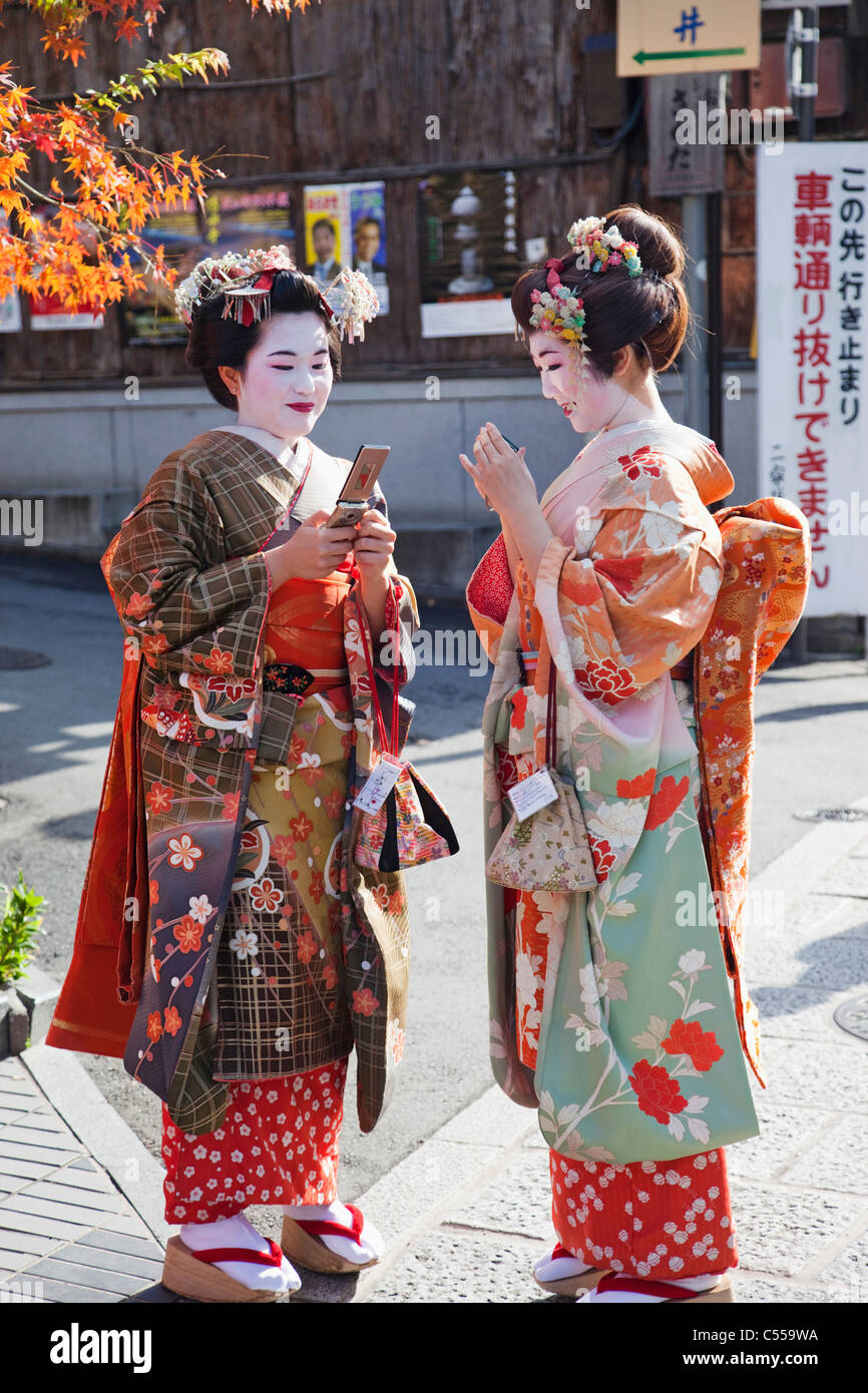 Deux femmes habillées en kimono Geisha en utilisant les téléphones mobiles,  Quartier Higashiyama, Kyoto Prefecture, Kinki Region, Honshu, Japan Photo  Stock - Alamy