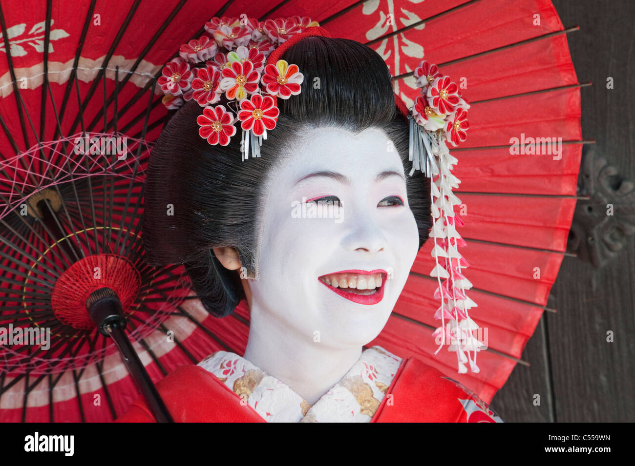 Jeune femme tenant un parasol et souriant Banque D'Images