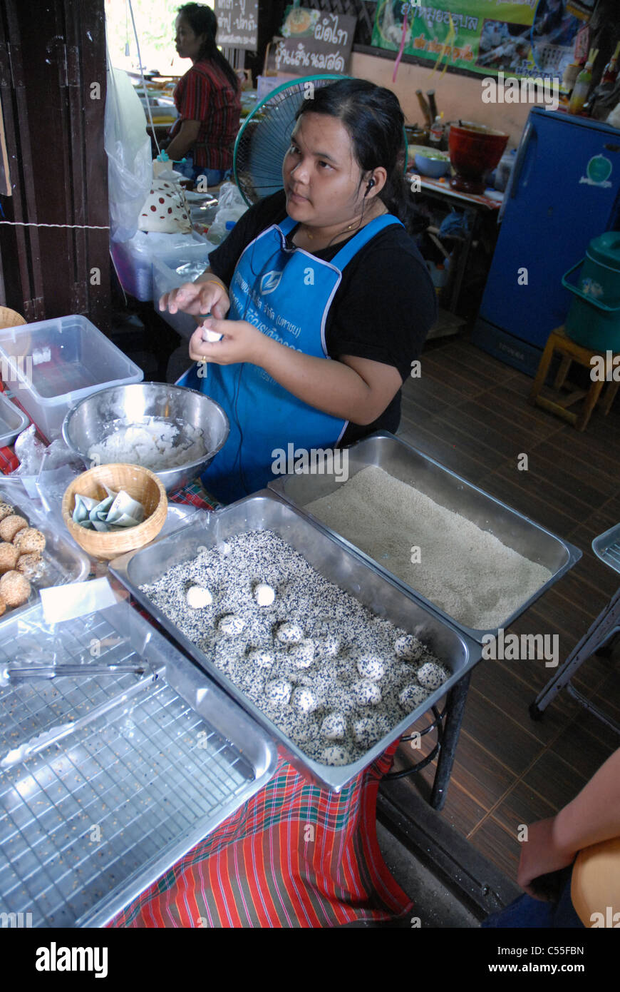 Un vendeur de rue préparant et emballant des encas thaïlandais traditionnels (Jian Dui) à un étal de marché animé, Bangkok, Thaïlande. Banque D'Images