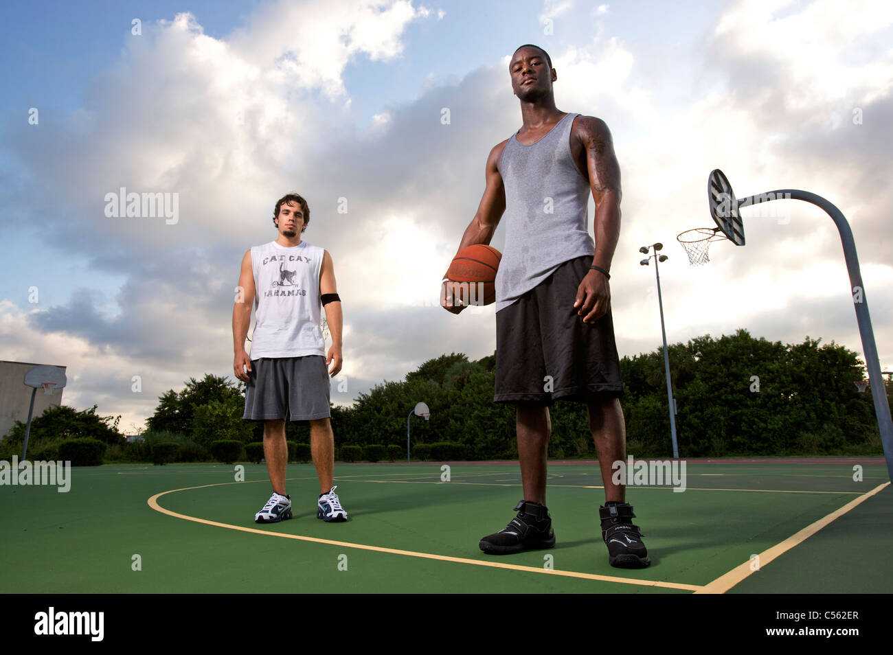 Les mâles après après avoir joué au basket-ball sur une cour, ciel dramatique Banque D'Images