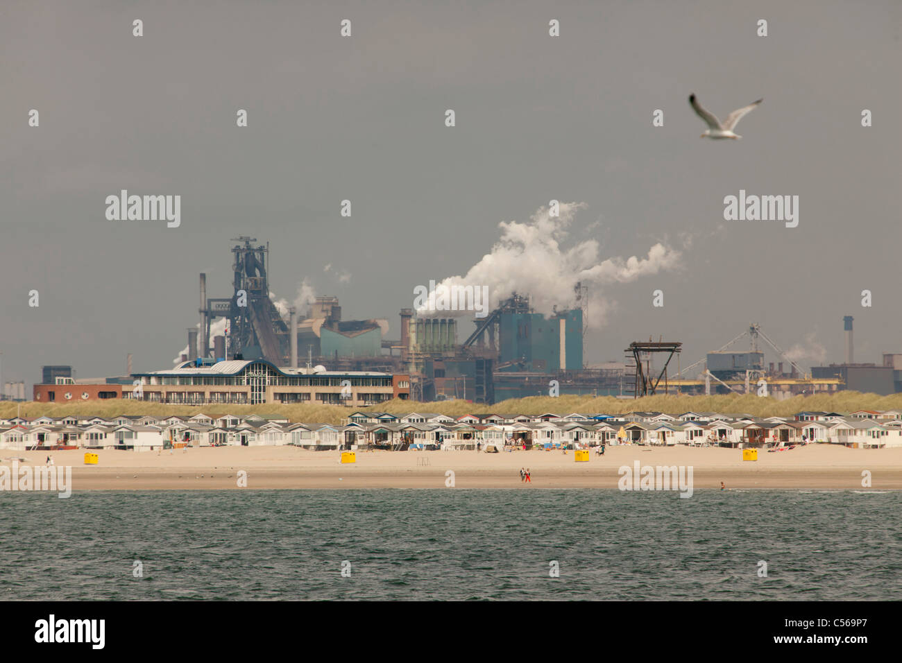 Les Pays-Bas, IJmuiden, cabines de plage. Contexte Tata Steel factory, les hauts fourneaux. Banque D'Images