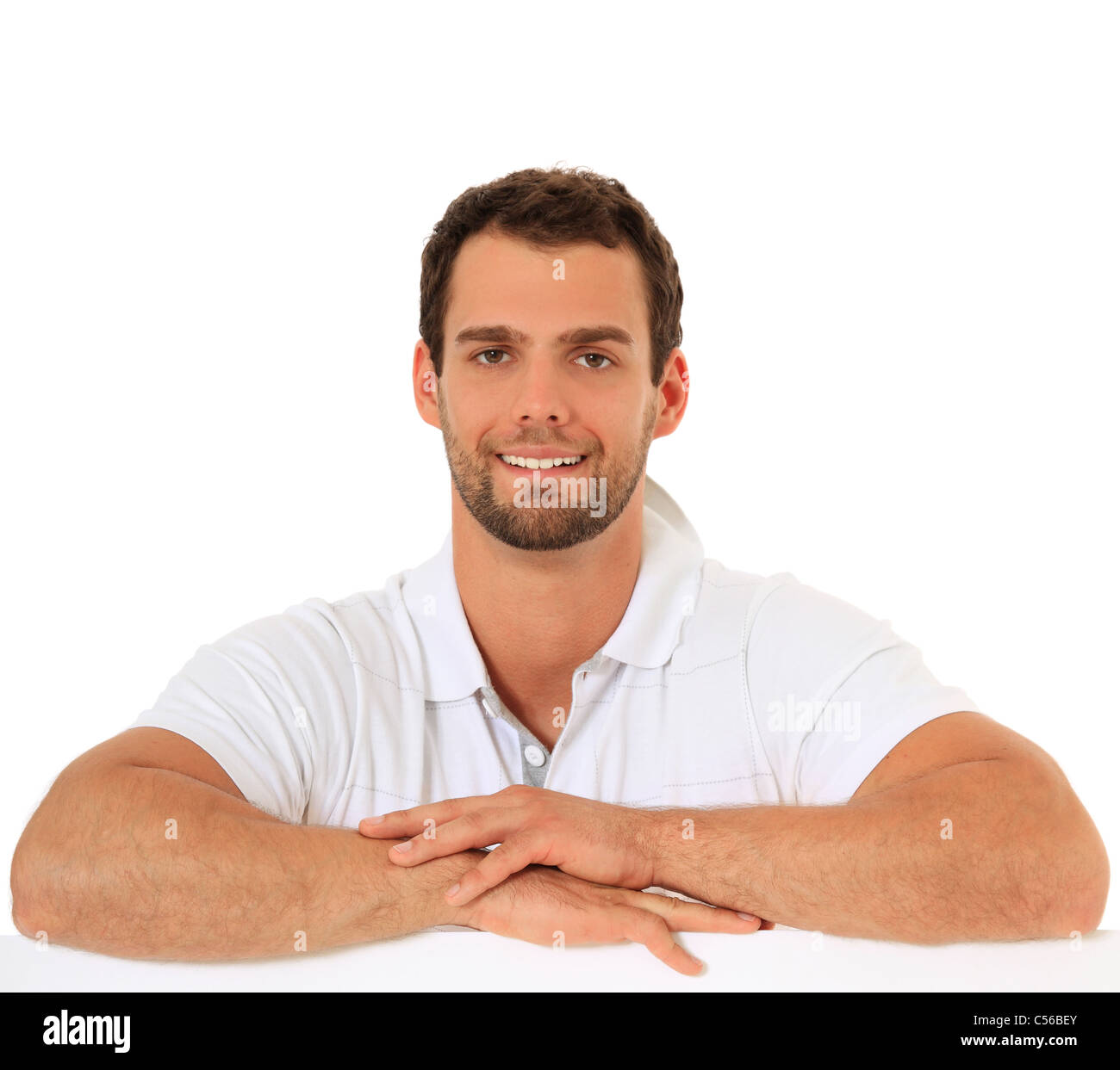 Young guy debout derrière mur blanc. Le tout sur fond blanc. Banque D'Images