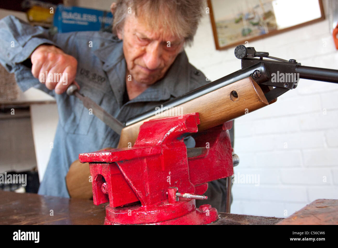 Un homme âgé dans son 80's la réparation d'un canon de fusil dans son atelier, Banque D'Images