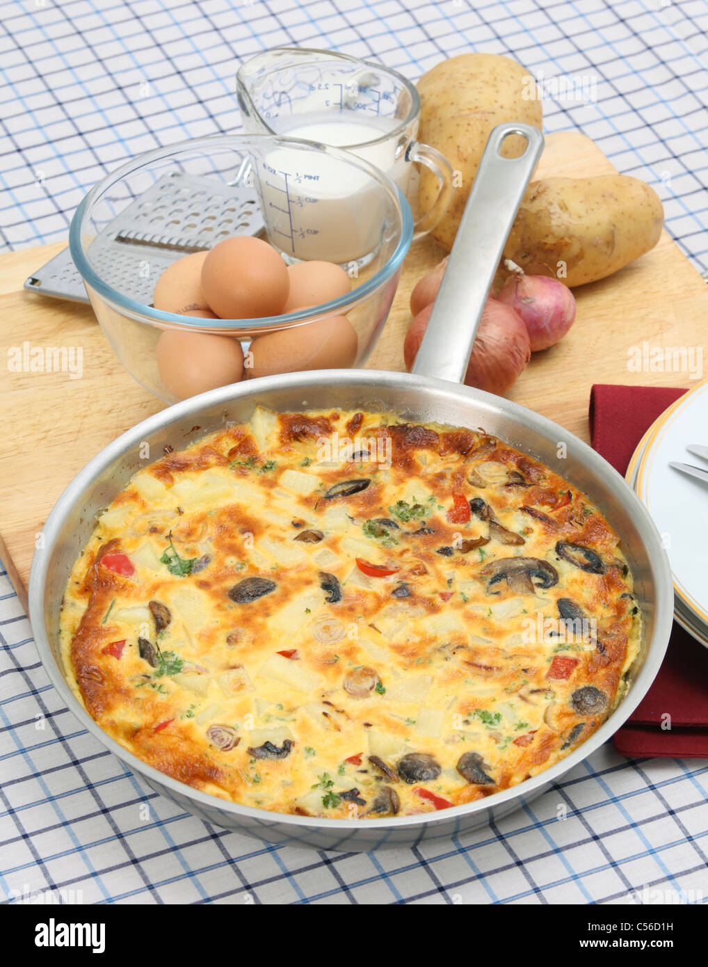 Un petit-déjeuner fraîchement préparé l'omelette espagnole ou de tortilla de patates toujours dans la casserole, avec des ingrédients essentiels derrière Banque D'Images