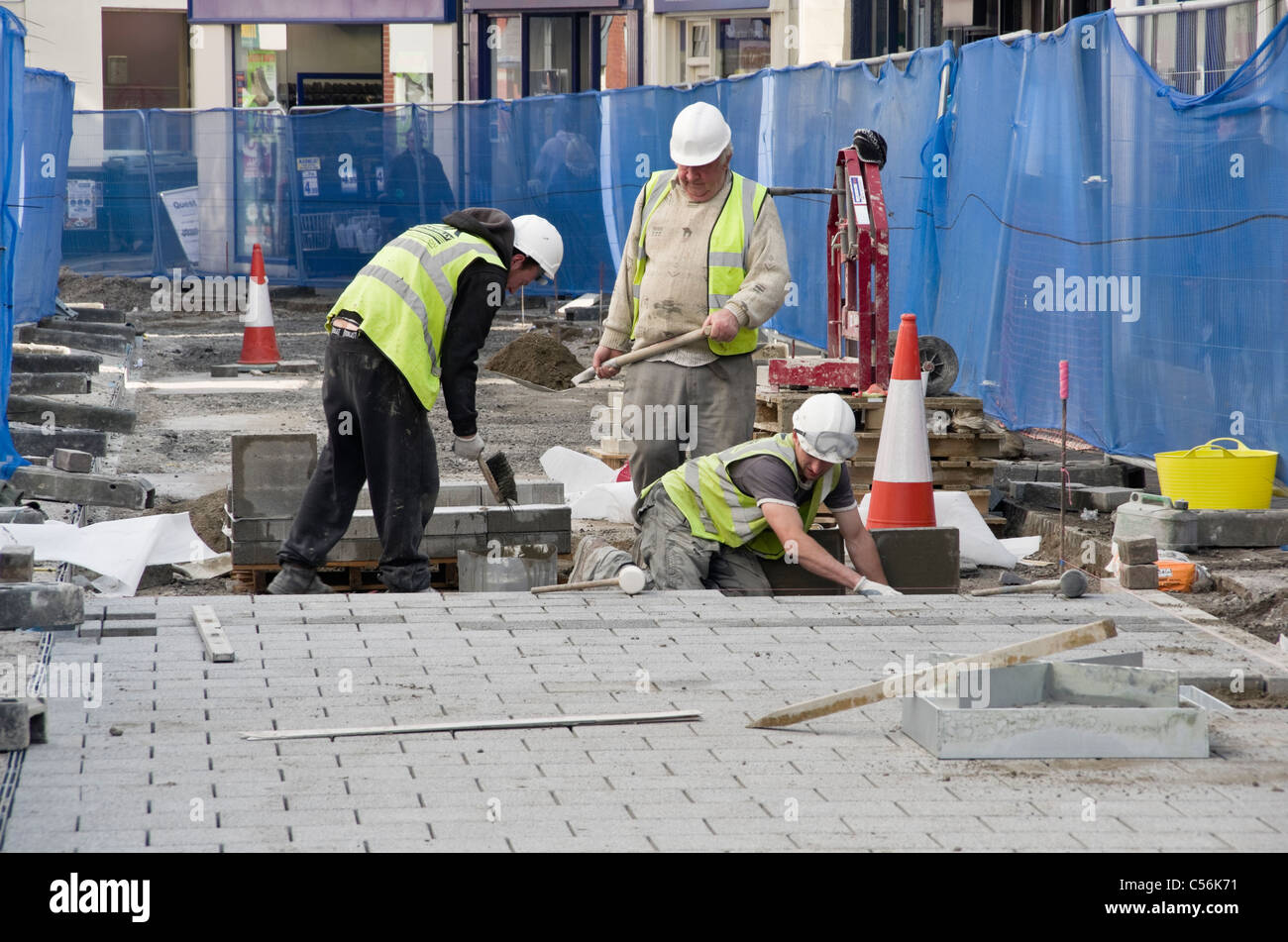High Street, Bangor, Gwynedd, au nord du Pays de Galles, Royaume-Uni. Conseil des ouvriers creusant jusqu'à la route du remplacement de pavés dans la cité Banque D'Images
