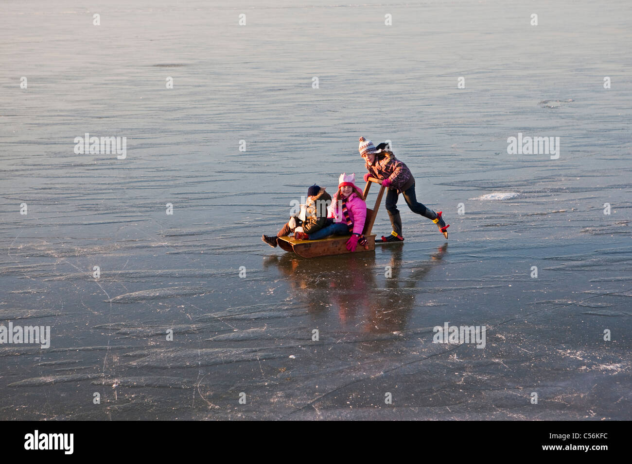 Les Pays-Bas, Marken, enfants à traineau en patinage sur glace d'un lac appelé IJsselmeer. Banque D'Images