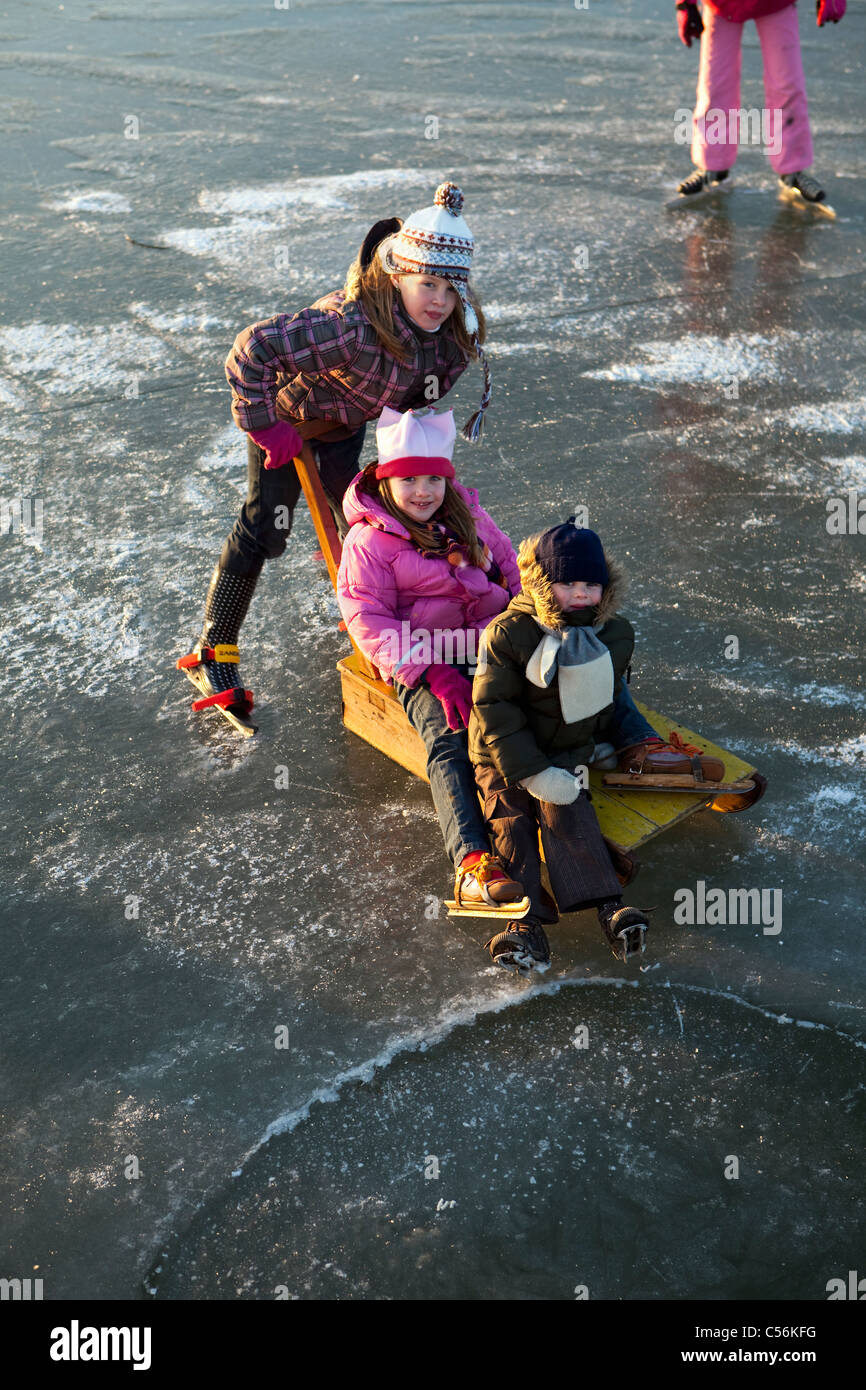 Les Pays-Bas, Marken, enfants à traineau en patinage sur glace d'un lac appelé IJsselmeer. Banque D'Images