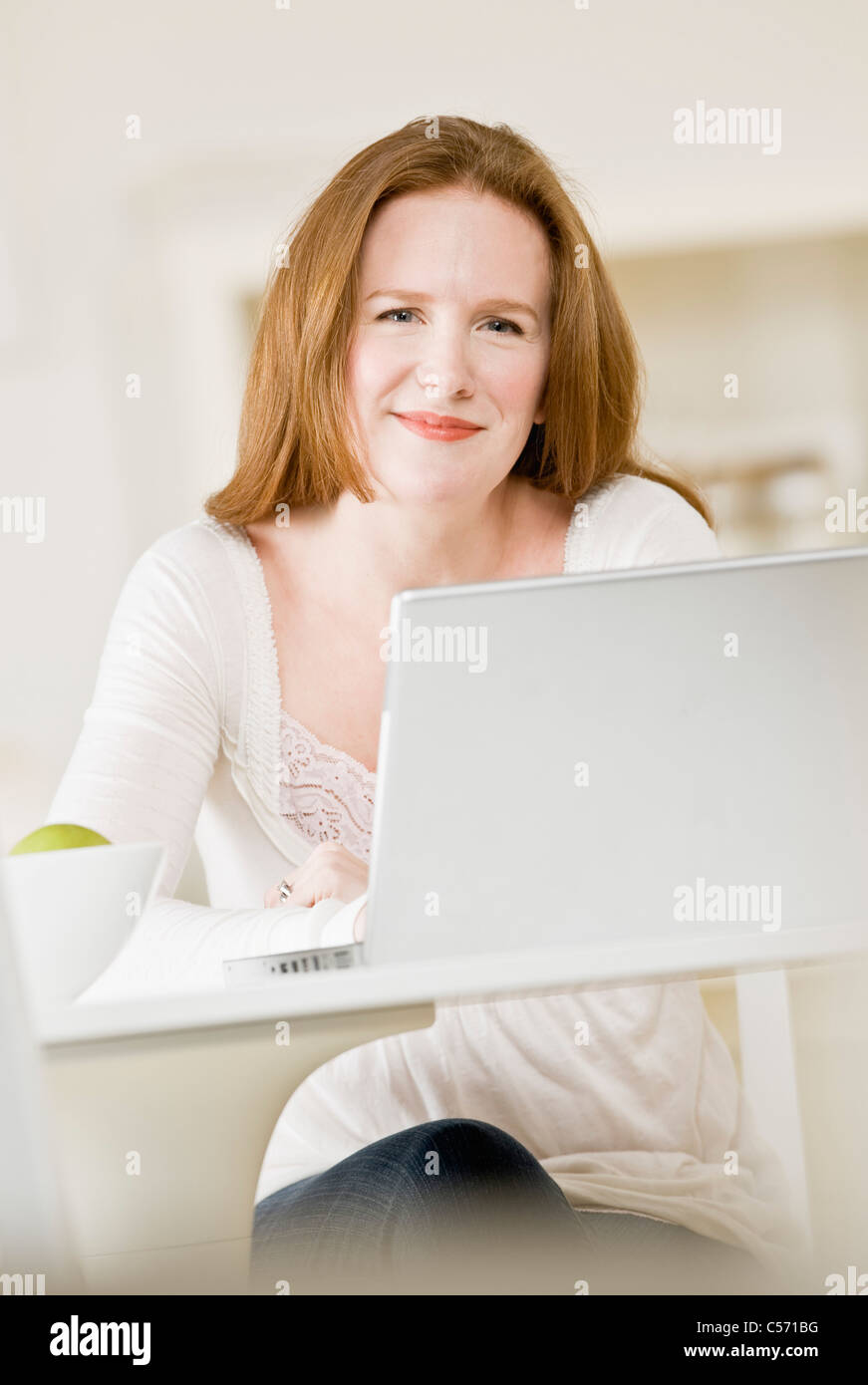 Smiling woman using laptop Banque D'Images