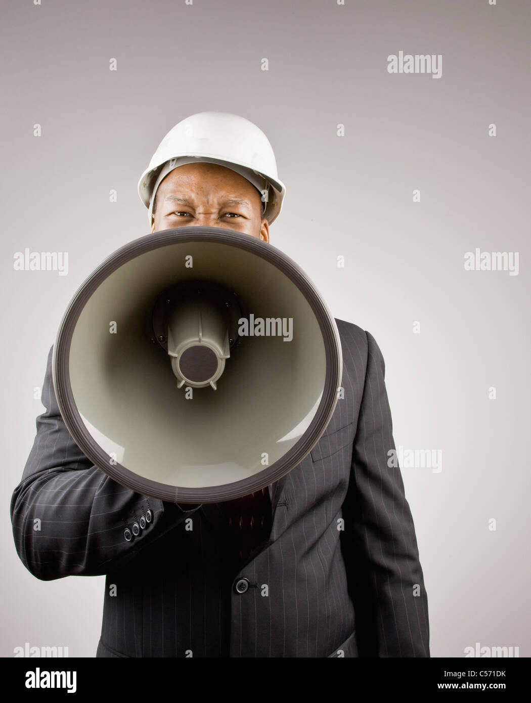 Businessman in hard hat en utilisant megaphone Banque D'Images