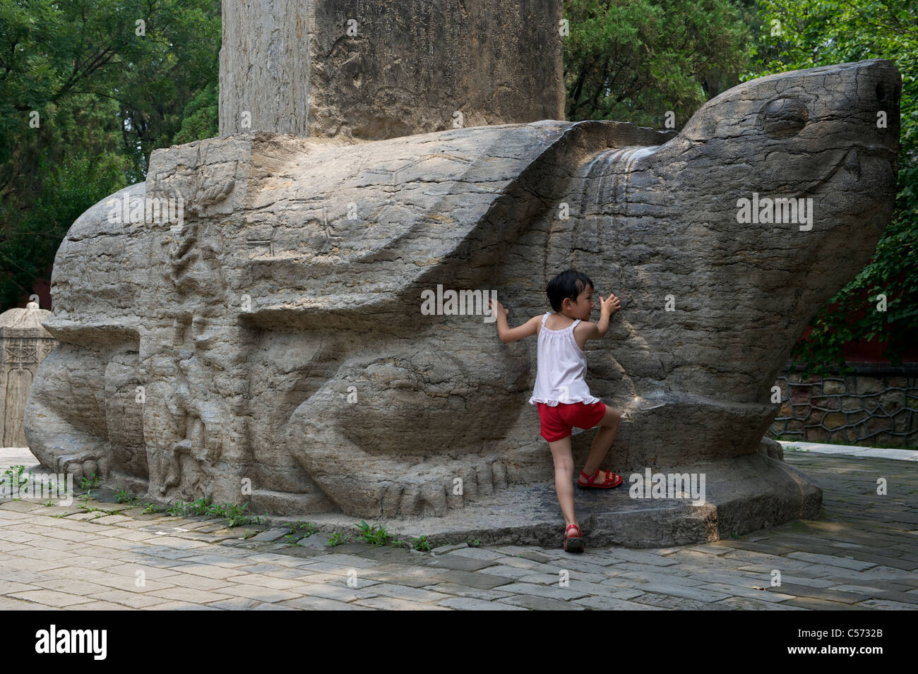 Une fille se tient près d'un Bixi au temple Dai à Shandong, en Chine.10 juillet 2011 Banque D'Images