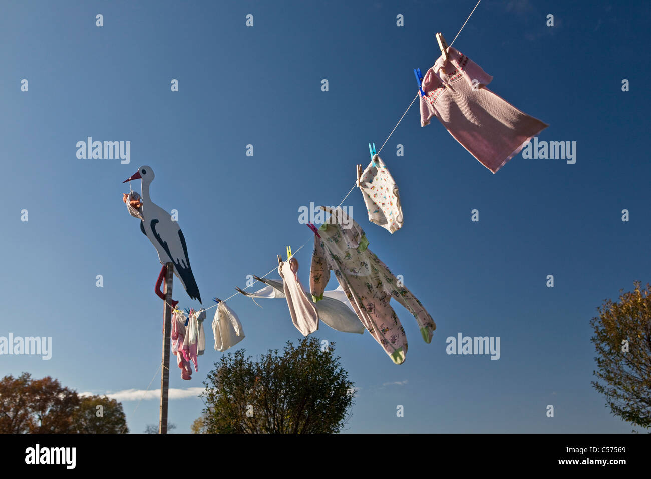 Les Pays-Bas, Lattrop, Stork en bois avec baby doll, pour montrer qu'un bébé est né. Vêtements de bébé sur corde à linge. Banque D'Images