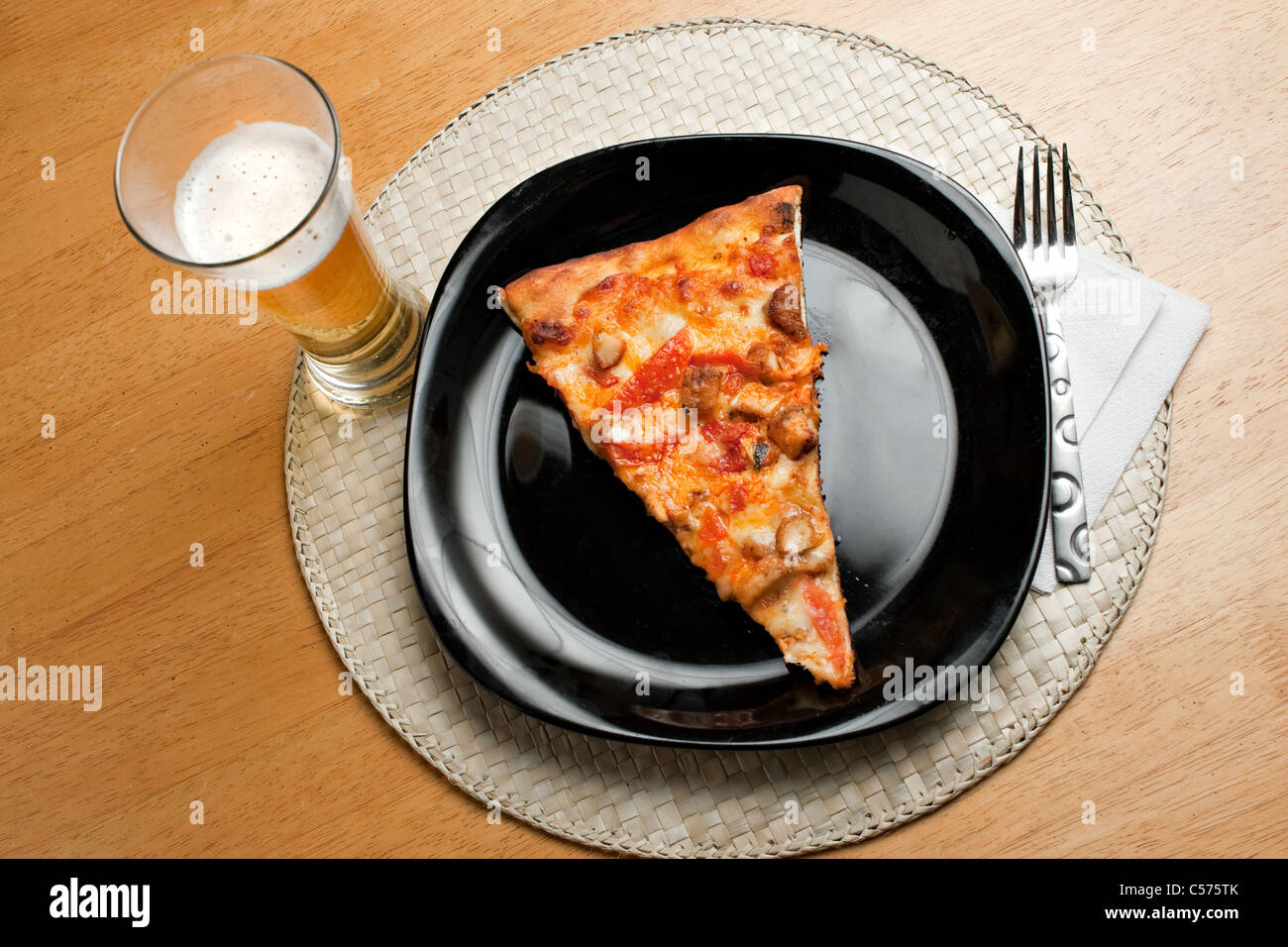 Une seule tranche de pizza au poulet Buffalo et un verre de bière légère. Banque D'Images