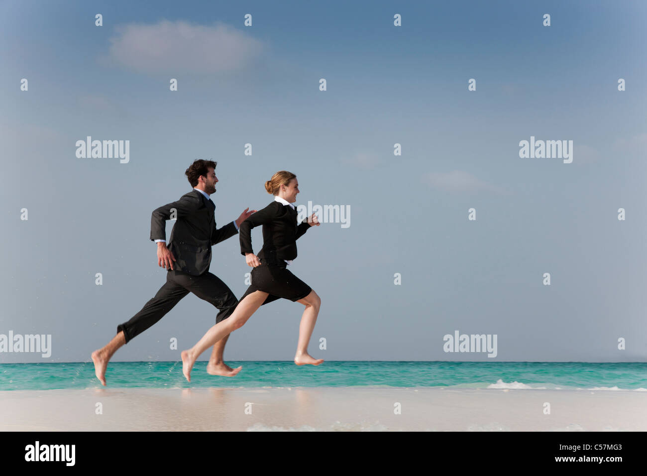 Les gens d'affaires running on beach Banque D'Images